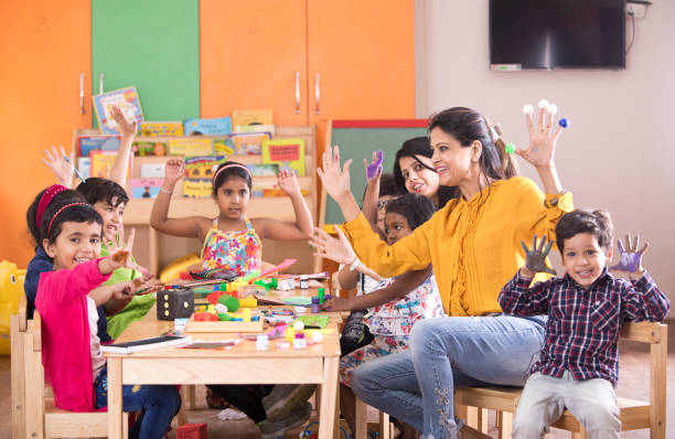 Teacher with preschool students having fun while finger painting at class
