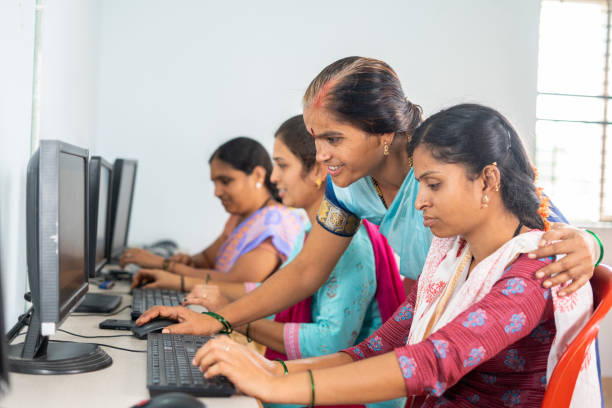 Teacher helping or teaching students during computer class training - concept of learning, personal support and technology
